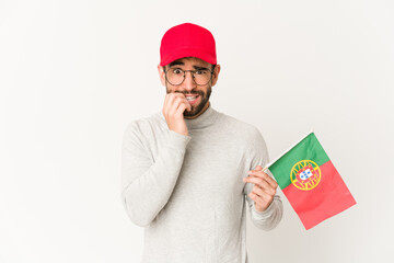 Young hispanic mixed race woman holding a portugal flag biting fingernails, nervous and very anxious.