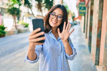 Young hispanic businesswoman smiling happy doing video call using smartphone at the city.