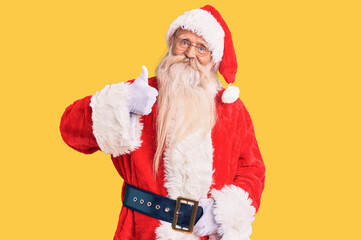 Fototapeta na wymiar Old senior man with grey hair and long beard wearing traditional santa claus costume doing happy thumbs up gesture with hand. approving expression looking at the camera showing success.