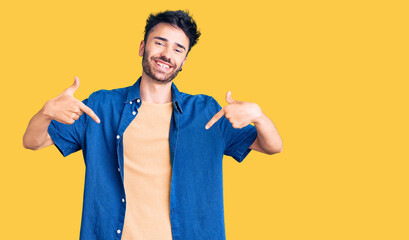 Young hispanic man wearing casual clothes looking confident with smile on face, pointing oneself...