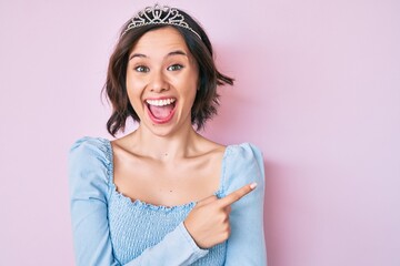 Young beautiful girl wearing princess crown celebrating crazy and amazed for success with open eyes screaming excited.