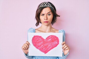 Young beautiful girl wearing princess crown holding heart draw skeptic and nervous, frowning upset because of problem. negative person. © Krakenimages.com