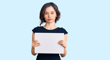 Naklejka premium Young beautiful girl holding blank empty banner thinking attitude and sober expression looking self confident