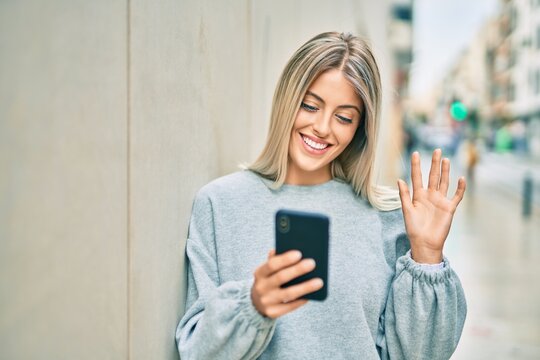Young blonde girl smiling happy doing video call using smartphone at the city