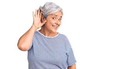 Senior woman with gray hair wearing casual striped clothes smiling with hand over ear listening an...
