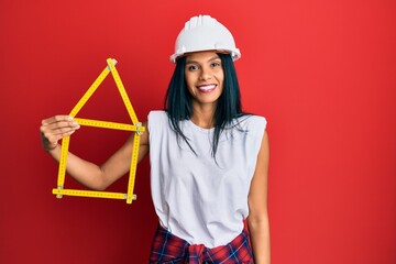 Young african american woman wearing architect hardhat holding build project looking positive and...