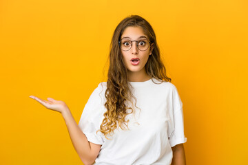 Young caucasian woman impressed holding copy space on palm.