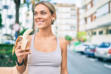 Young cauciasian fitness woman wearing sport clothes training outdoors eating healthy banana for strength and energy © Krakenimages.com