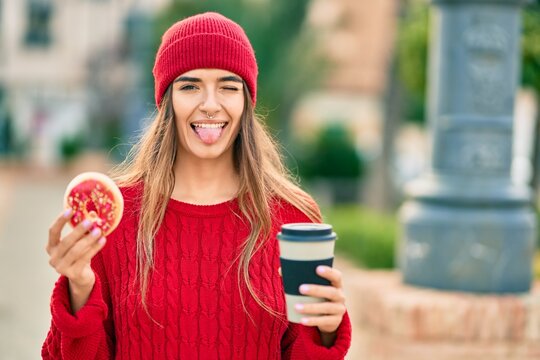 Young hispanic woman wearing wool cap having breakfast at the city.