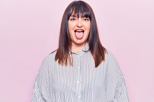 Young plus size woman wearing casual clothes sticking tongue out happy with funny expression. emotion concept.