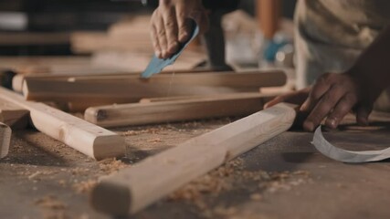 Closeup of unrecognizable craftsman sanding piece of wood with sandpaper blowing out sawdust from table working in joinery - Powered by Adobe