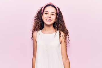 Beautiful kid girl with curly hair wearing casual clothes looking positive and happy standing and...