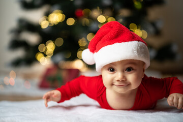 adorable little baby boy in a santa costume lying on a soft fake fur in front of a christmas tree