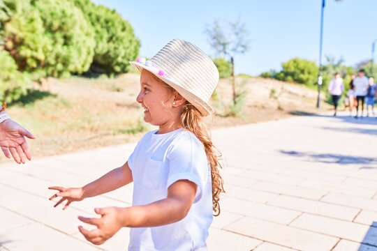 Adorable blonde child wearing summer hat smiling happy. Standing with smile on face around the park