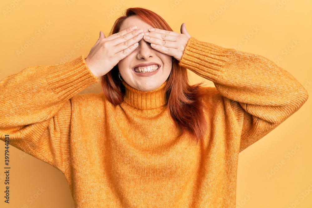 Poster beautiful redhead woman wearing casual winter sweater over yellow background covering eyes with hand