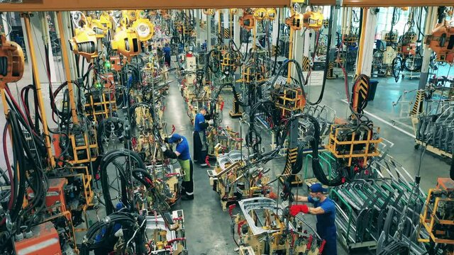 Several car factory workers welding car parts on an assembly line. Timelapse