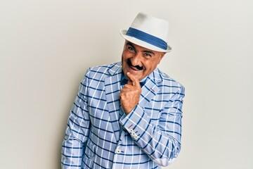 Mature middle east man with mustache wearing vintage and elegant fashion style smiling looking confident at the camera with crossed arms and hand on chin. thinking positive.