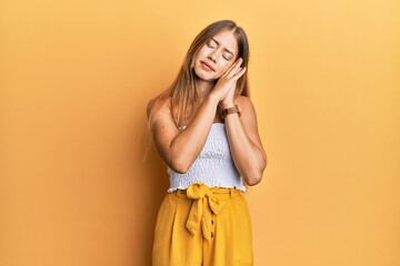 Beautiful young blonde woman wearing casual summer clothes sleeping tired dreaming and posing with hands together while smiling with closed eyes.