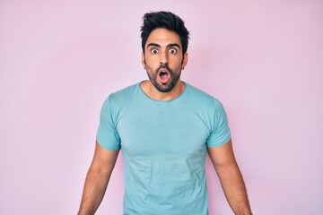 Handsome hispanic man with beard wearing casual clothes afraid and shocked with surprise expression, fear and excited face.
