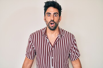 Handsome hispanic man with beard wearing casual clothes scared and amazed with open mouth for surprise, disbelief face
