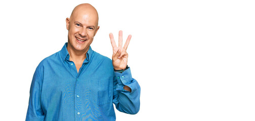 Middle age bald man wearing casual clothes showing and pointing up with fingers number three while smiling confident and happy.