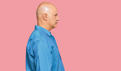 Middle age bald man wearing casual clothes looking to side, relax profile pose with natural face...
