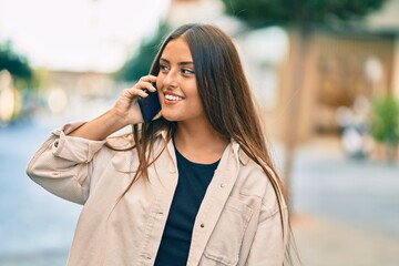 Young hispanic girl smiling happy talking on the smartphone at the city.