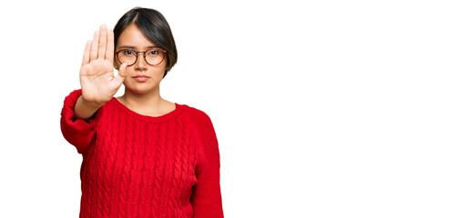 Young beautiful hispanic woman with short hair wearing casual sweater and glasses doing stop sing...