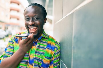 Young african american man talking on the smartphone leaning on the wall at street of city.
