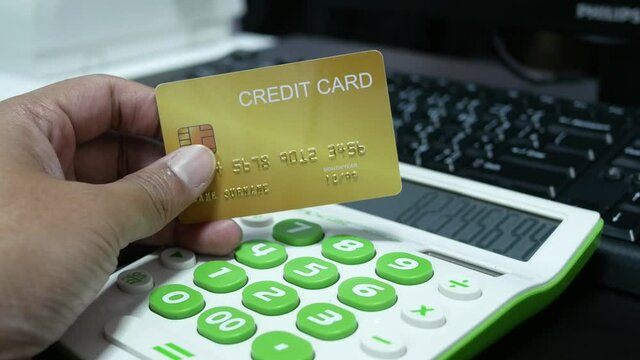 hand holding creadit card with calculator for shopping online.
