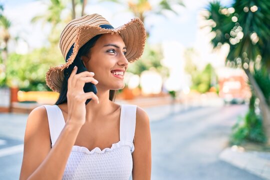Young latin girl wearing summer style talking on the smartphone at street of city.