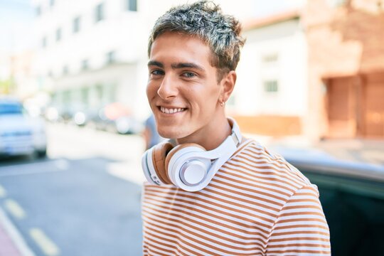 Young handsome caucasian man smiling happy wearing headphones walking at city.