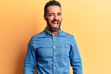 Young hispanic man wearing casual clothes winking looking at the camera with sexy expression,...