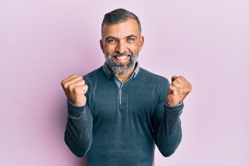Fototapeta premium Middle age handsome man wearing casual clothes celebrating surprised and amazed for success with arms raised and open eyes. winner concept.