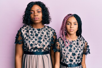 Beautiful african american mother and daughter wearing sexy party dress with serious expression on face. simple and natural looking at the camera.