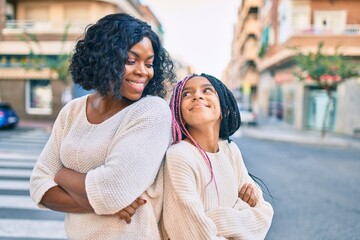 Beautiful african american mother and daughter smiling happy and hugging. Standing with smile on face standing at the city.