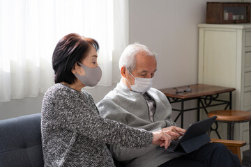 Obraz premium マスクをつけてタブレットPCを見る日本人シニア夫婦
