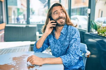 Young middle eastern man talking on the smartphone at coffee shop.