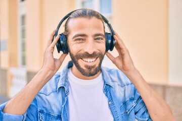 Young middle eastern man smiling happy using headphones at the city.