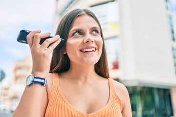 Young middle east girl smiling happy listening audio message using smartphone at the city.