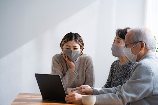 マスクをつけてノートパソコンを見る日本人親子・二世代家族