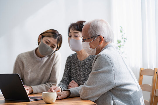 マスクをつけてノートパソコンを見る日本人親子・二世代家族