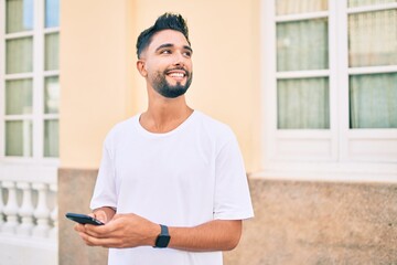 Fototapeta premium Young arab man smiling happy using smartphone at the city.