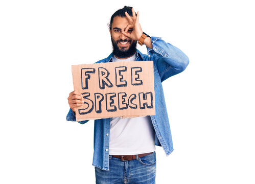 Young arab man holding free speech banner smiling happy doing ok sign with hand on eye looking through fingers