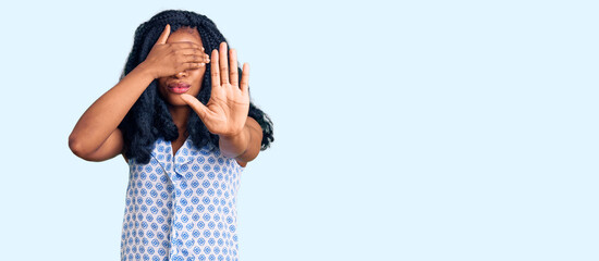 Beautiful african american woman wearing casual summer shirt covering eyes with hands and doing stop gesture with sad and fear expression. embarrassed and negative concept.