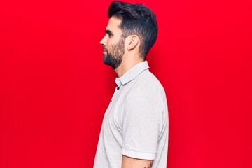 Young handsome man with beard wearing casual polo looking to side, relax profile pose with natural...