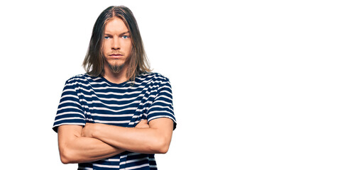 Handsome caucasian man with long hair wearing casual striped t-shirt skeptic and nervous,...