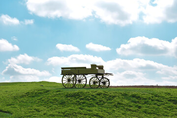 Fototapeta na wymiar Antique wagon on the green grass and blue sky is background.