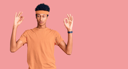 Young african american man wearing sportswear relax and smiling with eyes closed doing meditation gesture with fingers. yoga concept.