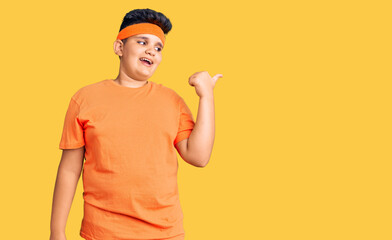 Little boy kid wearing sportswear smiling with happy face looking and pointing to the side with thumb up.